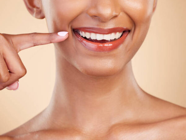 Closeup, smile and mouth of woman in studio for dental, cleaning and hygiene treatment on brown background. Zoom, lips and teeth whitening for happy girl smiling after veneers, braces or oral care